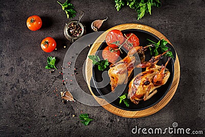 Baked quails in pan on a dark background. Top view. Stock Photo