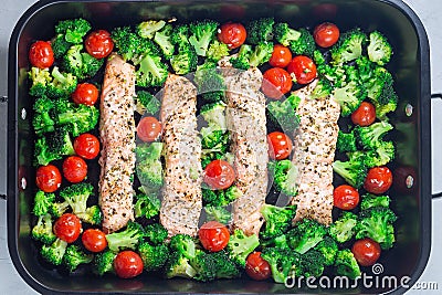 Baked salmon fillet with broccoli and tomato on frying tray, horizontal, top view Stock Photo