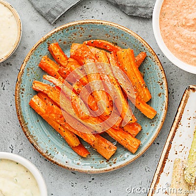 Baked season carrot sticks with sauce and hummus. Vegetarian healthy food Stock Photo