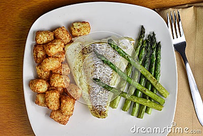 baked season cod with asparagus and tater tots Stock Photo