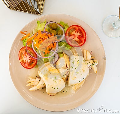 Baked sepia served with side dish of fresh vegetable salad Stock Photo