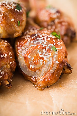 Baked spicy chicken legs with sesame and parsley on paper background Stock Photo