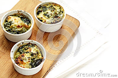 Baked spinach with cheese in three small casserole dishes on a Stock Photo