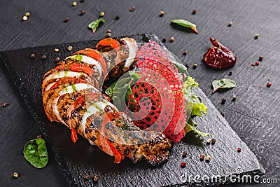 Baked Veal with mozzarella cheese, tomatoes, pesto sauce and green salad on black background. Hot Meat Dishes. Top view, flat lay Stock Photo