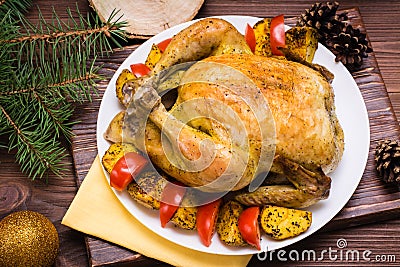 Baked whole chicken with a garnish of potatoes and tomatoes Stock Photo