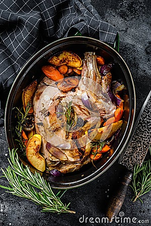 Baked whole lamb shoulder leg in a baking dish. Black background. Top view Stock Photo