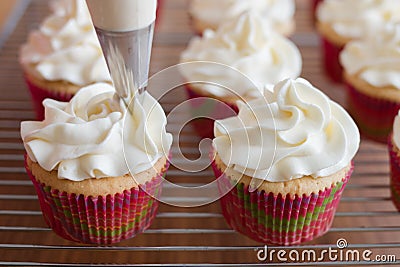 Baker decorates muffins with cream and confectionery nozzles Stock Photo