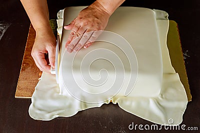 Baker decorating square cake with white fondant Stock Photo