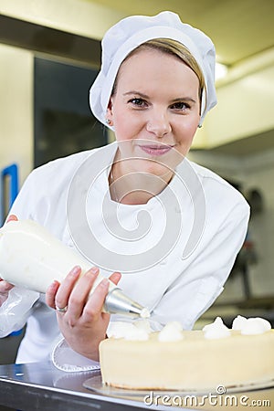 Baker prepares cake in bakehouse with whipped cream Stock Photo