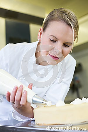 Baker prepares cake in bakehouse with whipped cream Stock Photo