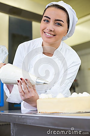 Baker prepares cake in bakehouse with whipped cream Stock Photo