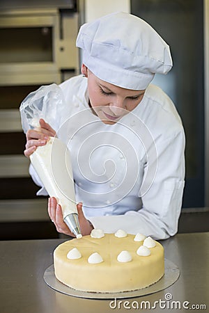 Baker prepares cake in bakehouse with whipped cream Stock Photo