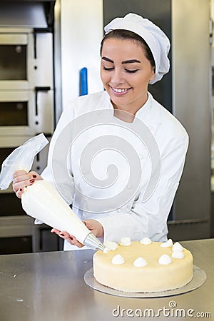 Baker prepares cake in bakehouse with whipped cream Stock Photo