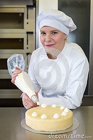 Baker prepares cake in bakehouse with whipped cream Stock Photo