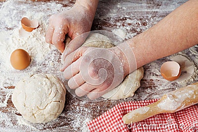 Baker prepares the dough on a wooden table, chef knead the dough with flour, homemade dough for bread or pizza Stock Photo