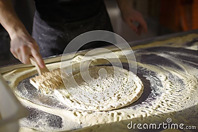 Baker prepares the pizza base so that it is porous Stock Photo