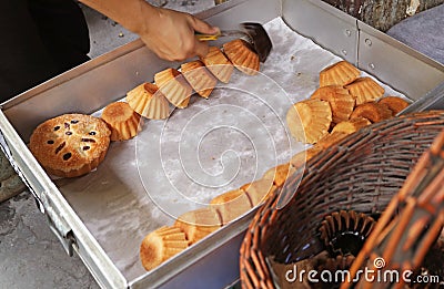 Baker Removing Heap of Freshly Baked Kudeejeen Cupcakes or Khanom Farang Kudeejeen from the Mold Stock Photo