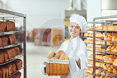 A baker woman holding a basket of baked in her hands at the bakery Stock Photo