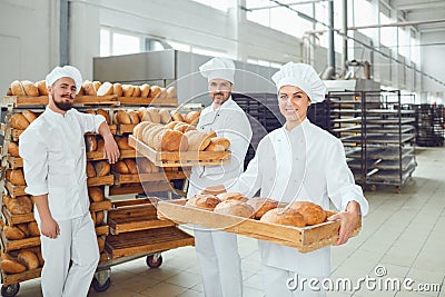 Bakers hold a tray with fresh bread in the bakery. Stock Photo