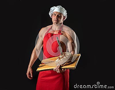 Bakery advertising. Cooking and baking. Chef baker man in apron. Sexy guy with bread and knife. Stock Photo