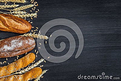 Bakery background top view. Crusty buns and loaves of bread on dark grey chalkboard background. Blurred background Stock Photo