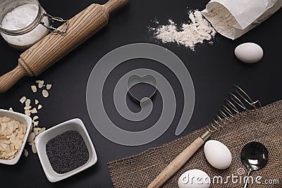 Baking love. Bakery background. Baking ingredients and kitchen utensils on the black background. Flour, almond nuts, eggs. Top Stock Photo