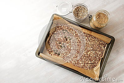 Baking tray with dough from linseed and oat flakes, cut into rhombs and topped with various seeds for healthy pastry snacks, copy Stock Photo