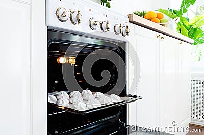 Baking tray with sweet meringues in the oven on kitchen Stock Photo