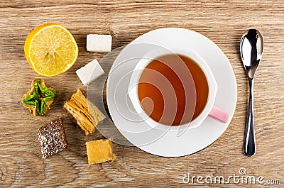 Baklava, lemon, sugar, cup with tea on saucer, teaspoon on table. Top view Stock Photo