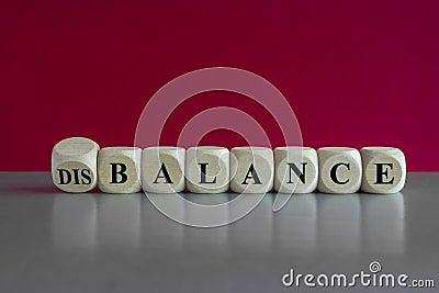 Balance or disbalance symbol. Turned a cube and changes the word disbalance to balance. Beautiful red background, grey table, copy Stock Photo