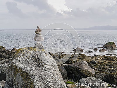 Balance stones on a rock with ocean and cloudy background. Concept hard work, goal achievement, insistence, tenacity Stock Photo