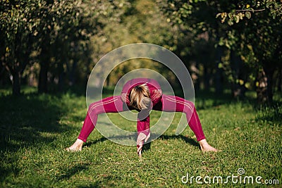 Balancing girl in red sportswear doing yoga pose on the alley in the autumn park Stock Photo