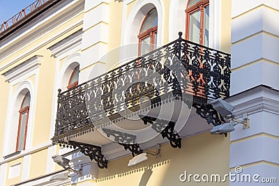 A balcony with an openwork wrought-iron parapet at the street in Stock Photo