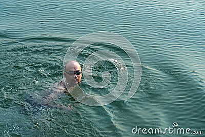 Bald adult man swimming in blue nature wave lake summer vacation background Stock Photo