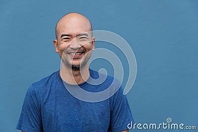 Bald beard smiling Japanese portrait man with t-shirt on cement blue wall Stock Photo