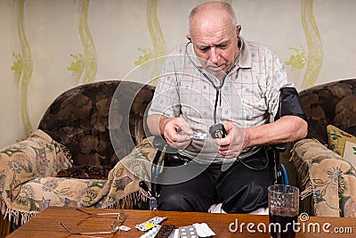 Bald Elderly Man with BP Apparatus and Medicines Stock Photo