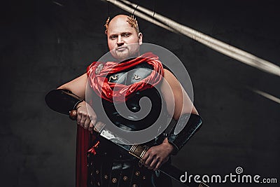 Bald empire soldier poses with sheathed sword in studio Stock Photo
