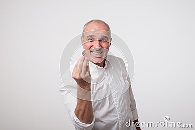 Bald handsome mature man looking angry showing italian gesture over white background. Stock Photo