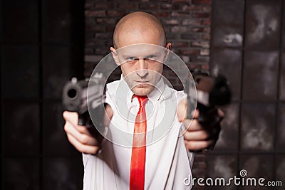 Bald hired killer in red tie aims a pistols Stock Photo