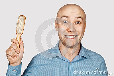 Bald man with alopecia holds a comb in his hand. concept absurdity Stock Photo