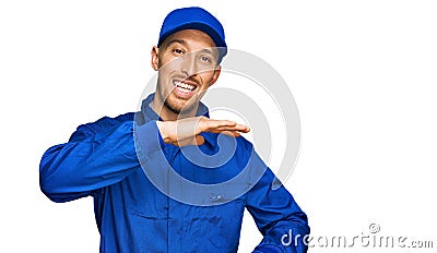 Bald man with beard wearing builder jumpsuit uniform gesturing with hands showing big and large size sign, measure symbol Stock Photo