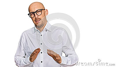 Bald man with beard wearing business shirt and glasses disgusted expression, displeased and fearful doing disgust face because Stock Photo