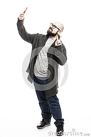 A bald man with glasses and a beard takes a selfie on the phone. Full height. Isolated on a white background. Stock Photo