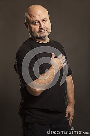 Bald middle-aged man, dark background Stock Photo