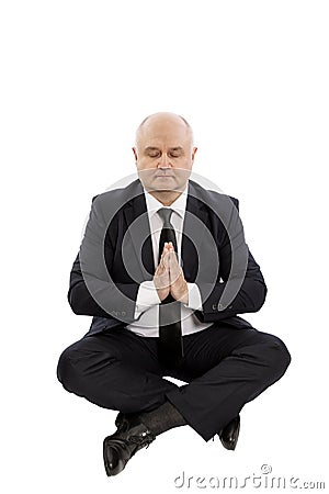 Bald middle-aged man in a suit sits in a yoga pose, hands in prayer, is isolated on a white background Stock Photo