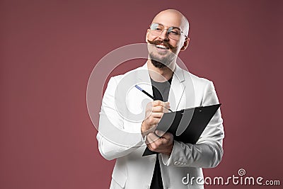 Balded man with mustache and beard in a business suit holding clipboard and pen isolated background.Concept of teacher Stock Photo