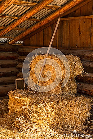 Bales of Straw Hay with Pitchfork in Barn Stock Photo