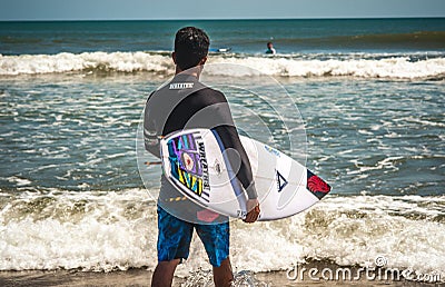 Male surfer on a beach preparing to catch some waves Editorial Stock Photo