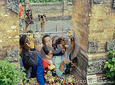 Young women behind iron bars are trying to sell various souvenirs to tourists in the streets of a town in Bali. Retro film Editorial Stock Photo