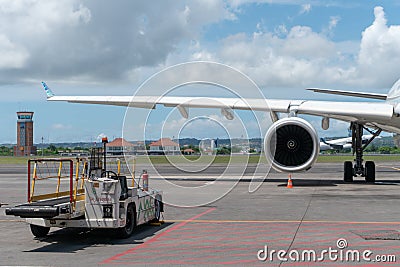 BALI/INDONESIA-MARCH 27 2019: Engine and main landing gear when aircraft park on apron in the airport with some vehicle near it. Stock Photo